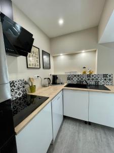 a kitchen with white cabinets and a stove top oven at Gîte les Pissenlits centre historique Saint-Astier in Saint-Astier +10 photos