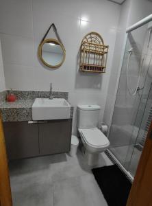 a bathroom with a toilet and a sink and a mirror at Apto Astúrias Guarujá in Guarujá