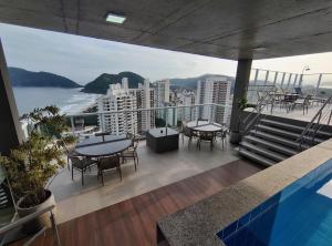 a balcony with tables and chairs and a view of the ocean at Apto Astúrias Guarujá in Guarujá
