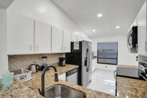 a kitchen with white cabinets and a stainless steel refrigerator at The Lake House in Fort Lauderdale in Fort Lauderdale