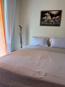 Una cama en un dormitorio con un cuadro en la pared. en Nectarios seaside apartment., en Palaión Tsiflíkion