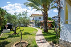 a garden with palm trees and a house at Anastasia's House in Toroni