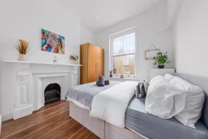 Dormitorio blanco con cama y chimenea en London living 2 BR Flat 2 mins to Clapahm Junction CJ, en Londres