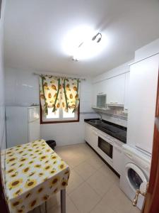 a white kitchen with a table and a stove at Apartamento Ribeira in Ribeira
