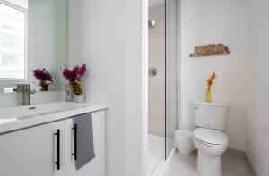 a white bathroom with a toilet and a sink at 2 Bedroom, 2 Bath Stunning Condo - heart of Kitchener Downtown in Kitchener +13 photos