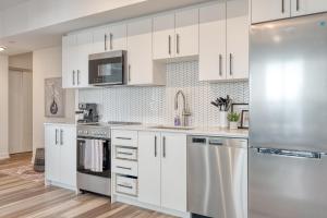 a kitchen with white cabinets and a stainless steel refrigerator at 2 Bedroom, 2 Bath Stunning Condo - heart of Kitchener Downtown in Kitchener