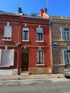 um edifício de tijolos vermelhos com uma porta numa rua em Amiénoise 5 chambres proche Centre Ville em Amiens