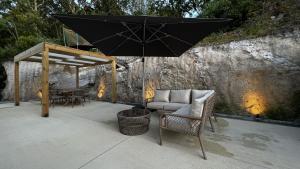 eine Terrasse mit einem schwarzen Regenschirm, einem Sofa und Stühlen in der Unterkunft Villa Gerês Emblematico - Piscina & Jacuzzi in Venda Nova