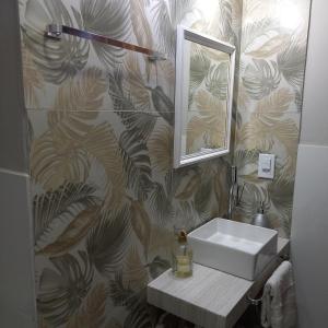 a bathroom with a sink and a mirror on a wall at Apart Coração de Búzios in Búzios