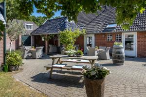 eine Terrasse mit einem Picknicktisch aus Holz und Stühlen in der Unterkunft Hotel B&B Hoeve de Vredenhof in Zuidlaren