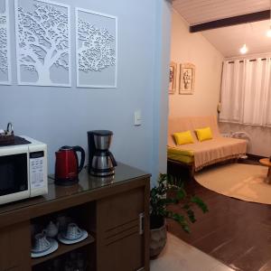 a kitchen with a microwave and a living room at Apart Coração de Búzios in Búzios