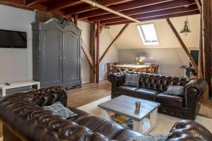 uma sala de estar com sofás de couro e uma mesa em Hotel B&B Hoeve de Vredenhof em Zuidlaren