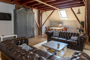 a living room with leather couches and a table at Hotel B&B Hoeve de Vredenhof in Zuidlaren