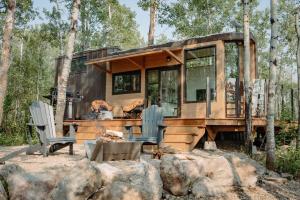 a tiny house in the woods with two chairs at Refuge Bay's Aqua Tiny Home - Luxury Off Grid Escape in Cherhill