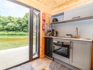 eine Küche in einem winzigen Haus mit einem großen Fenster in der Unterkunft Oak Lodge At Bridge Lake Farm & Fishery in Banbury