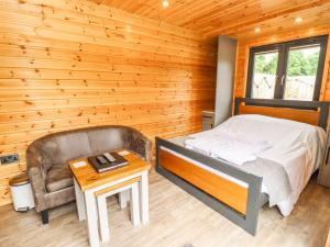 ein Schlafzimmer mit einem Bett, einem Stuhl und einem Tisch in der Unterkunft Oak Lodge At Bridge Lake Farm & Fishery in Banbury