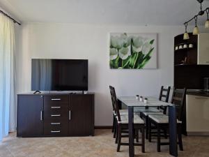 a dining room with a table and a tv at Apartment in the picturesque Oasis Resort & Spa in Lozenets