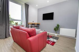 sala de estar con sofá rojo y TV en The Ojay's - Gustina Apartment, en Aberdeen