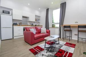 a living room with a red couch and a kitchen at The Ojay's - Gustina Apartment in Aberdeen