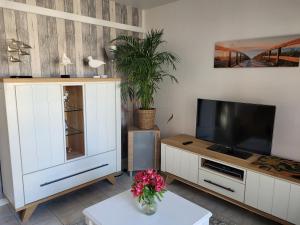 - un salon avec une télévision et une armoire blanche dans l'établissement Cosy one-bedroom apartment in De Haan, au Coq