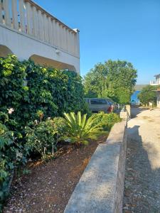 a sidewalk next to a building with a hedge at Apartman Skoko in Sevid