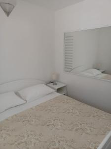 a white bedroom with a bed and a mirror at Apartman Skoko in Sevid