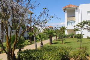 a park in front of a building with trees and bushes at Asilah Marina Golf, Appartement au calme in Asilah