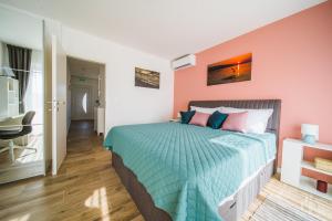 a bedroom with a bed with pink and blue sheets at Sunset Apartment in Orebić