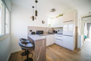 a kitchen with white cabinets and a blue stool at Sunset Apartment in Orebić