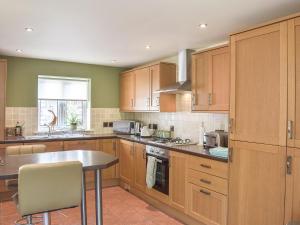 a kitchen with wooden cabinets and a table in it at Sorbie Villa in Stevenston