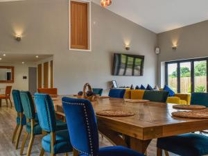 a dining room with a wooden table and blue chairs at Dodds Barn in Fersfield
