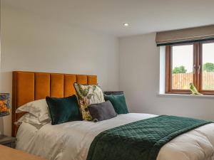 a bedroom with a large bed with a wooden headboard at Dodds Barn in Fersfield