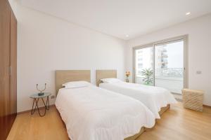 due letti in una stanza bianca con una finestra di anfa Louise a Casablanca