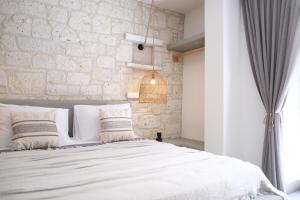 1 dormitorio con cama blanca y pared de piedra en Derin Alacati, en Alacati