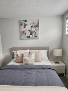 una camera da letto con un letto e un dipinto sul muro di 2-bedroom basement apartment a Calgary