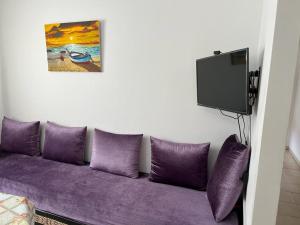 d'un canapé violet avec des oreillers violets et d'une télévision. dans l'établissement Appartement F3 en location d'été, à Fnideq
