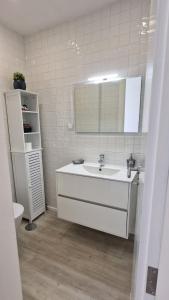 a white bathroom with a sink and a mirror at Ninho Citadino Aveiro in Aveiro