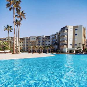 a large swimming pool with palm trees in front of a building at A Luxury 2BR with Big Pools Perfect for Family Summer Escape! in Monastir