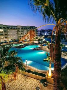een groot zwembad met palmbomen in een resort bij A Luxury 2BR with Big Pools Perfect for Family Summer Escape! in Monastir