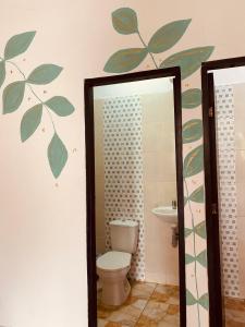 uma casa de banho com WC e folhas na parede em Casa Guiwa Hostel em Palomino