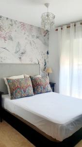 - une chambre avec un grand lit blanc et un lustre dans l'établissement Apartamento Julieta, à Estepona