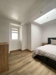 um quarto branco com uma cama e uma janela em L'Authentique - Terrasse - MyraConciergerie em Nay