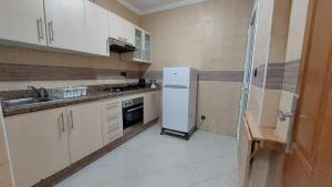 a kitchen with a white refrigerator and a sink at Appartement avec piscines, vue sur mer et accès à la plage à Achakar Hill, Tanger. in Tangier