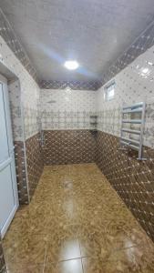 un bagno vuoto con una camera piastrellata e con doccia di Qafqaz Flower Villa a Gabala