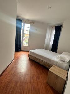 een slaapkamer met een bed en een houten vloer bij Hotel Artistico in Bogota