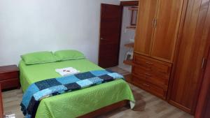 1 dormitorio con cama verde y armario de madera en Villa Almafe, en Villa de Leyva