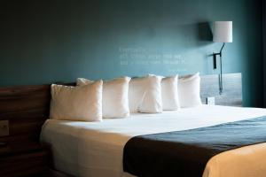 een bed met witte kussens en een citaat aan de muur bij Ruby River Hotel in Spokane