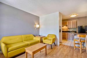 a living room with a yellow couch and a kitchen at Studio 6-San Antonio, TX - Six Flags in San Antonio