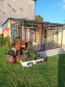 a greenhouse with plants and flowers in the grass at Chez Vladimir in Criquebeuf-en-Caux