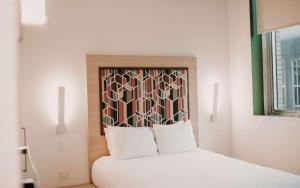 1 dormitorio con cama blanca y cabecero en CityFlatsHotel - Grand Rapids, Ascend Hotel Collection en Grand Rapids